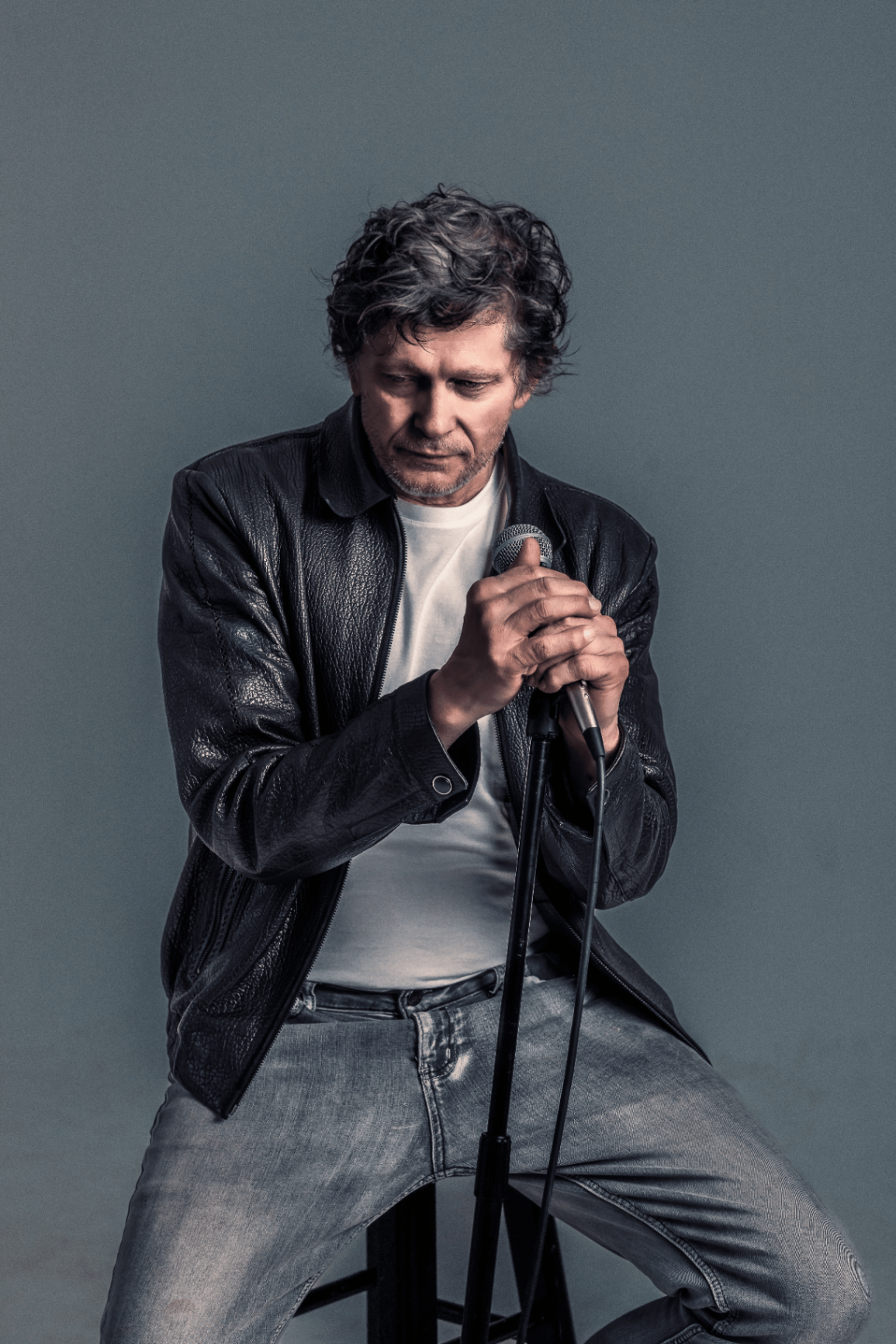 Portrait of Gregg Hodge with microphone, leather jacket